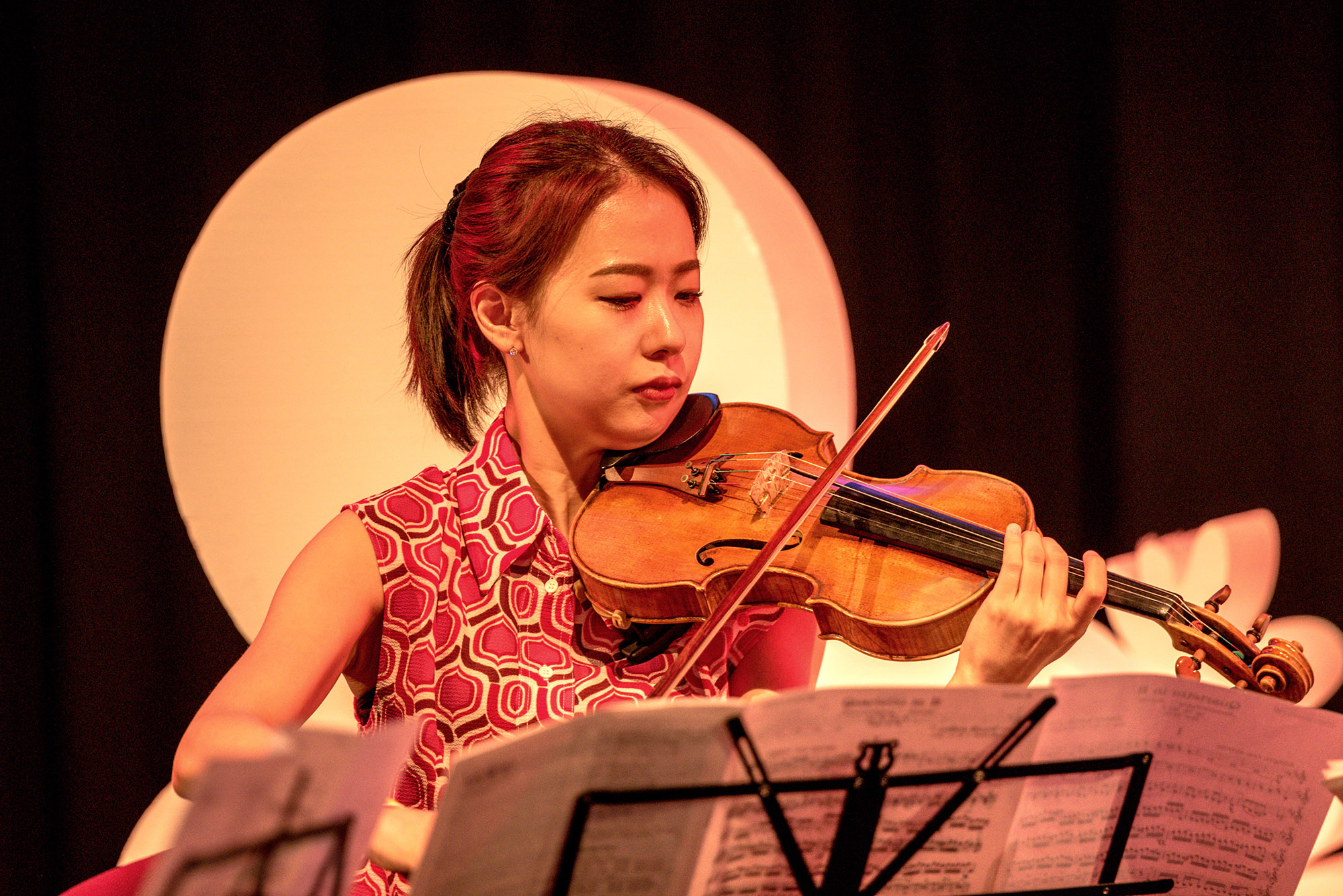 Eine Frau spielt Violine und hat einen Notenständer vor sich.
